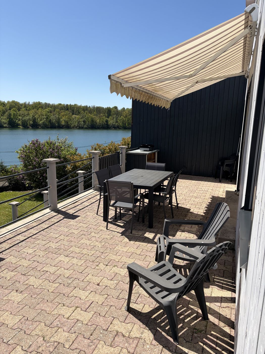 Terrasse avec store et salon de jardin, vue sur le lac